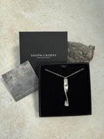 Cornish tin and diamond necklace in a South Crofty box on a textured surface. Next to a certificate of authenticity.